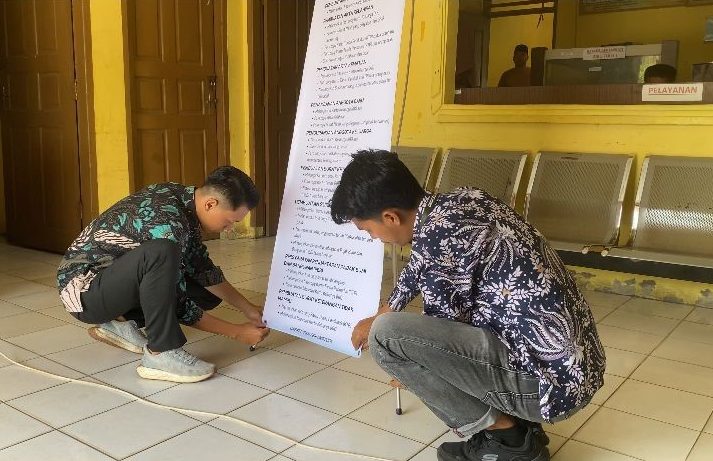 Mahasiswa KKN MBKM UNRI saat melakukan pemasangan stand banner. Foto: Tim KKN MBKM FISIP UNRI Kampung Tanjung Kuras