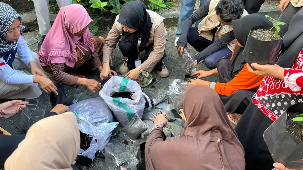 Mahasiswa KKN UNS saat mendampingi peserta saat mengaplikasikan sekam bakar untak tanaman dalam polibag. Foto: KKN UNS Desa Legundi