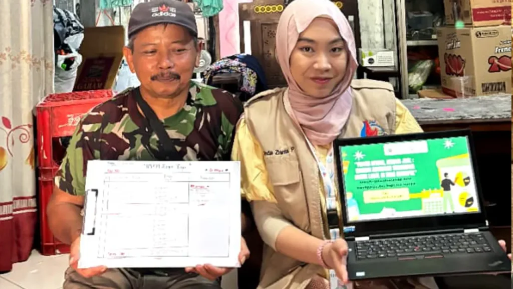 Seorang pelaku UMKM Desa Ngumpul bersama mahasiswa KKN UNS menunjukkan hasil pendampingan berupa tabel pencatatan keuangan manual dan materi edukasi digitalisasi usaha. (doc. KKN 225 UNS)