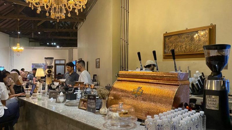 Seorang barista tampak meracik kopi di kafe bergaya klasik-modern yang tengah ramai pengunjung, Senin (8/12/2025).  Foto: Pribadi/Aprilia Setiani