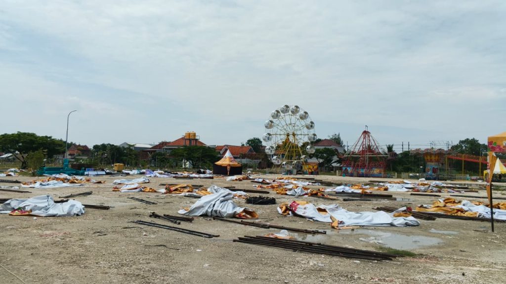 Kondisi Lapangan Gajah Mada, Lamongan, Minggu (20/12/2025), dipenuhi rangka besi dan terpal stan pasar malam yang roboh usai diterjang hujan deras disertai angin kencang. Foto: Pribadi