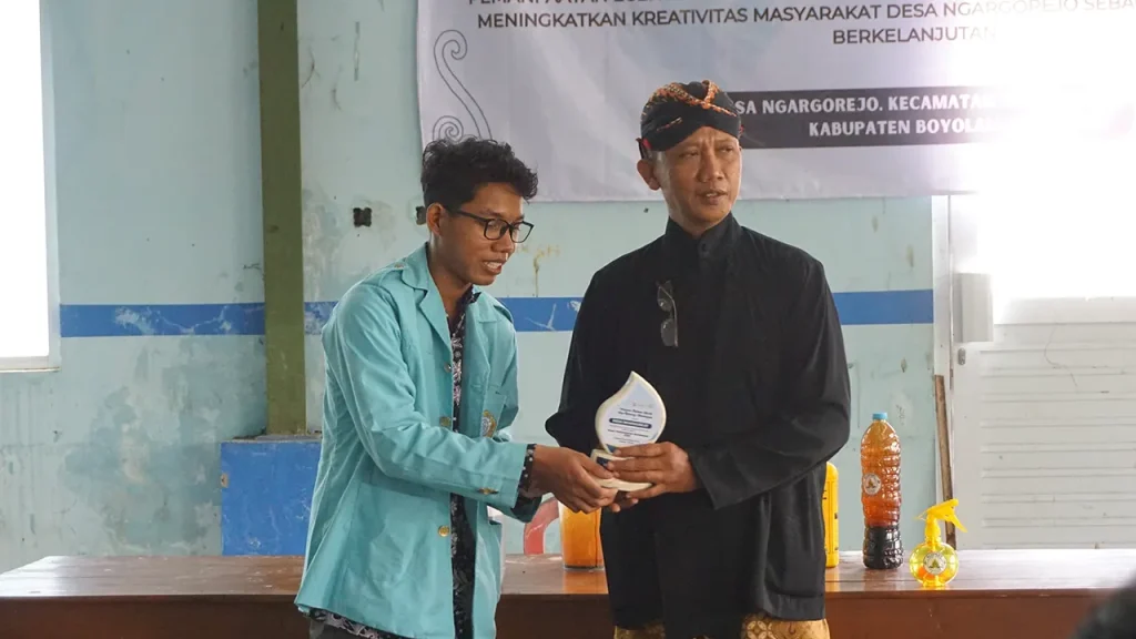 Mahasiswa Universitas Sebelas Maret (UNS) menyerahkan cenderamata kepada perwakilan Desa Ngargorejo pada kegiatan pemanfaatan eceng gondok menjadi pupuk organik cair di Waduk Cengklik, Boyolali. Foto: pribadi
