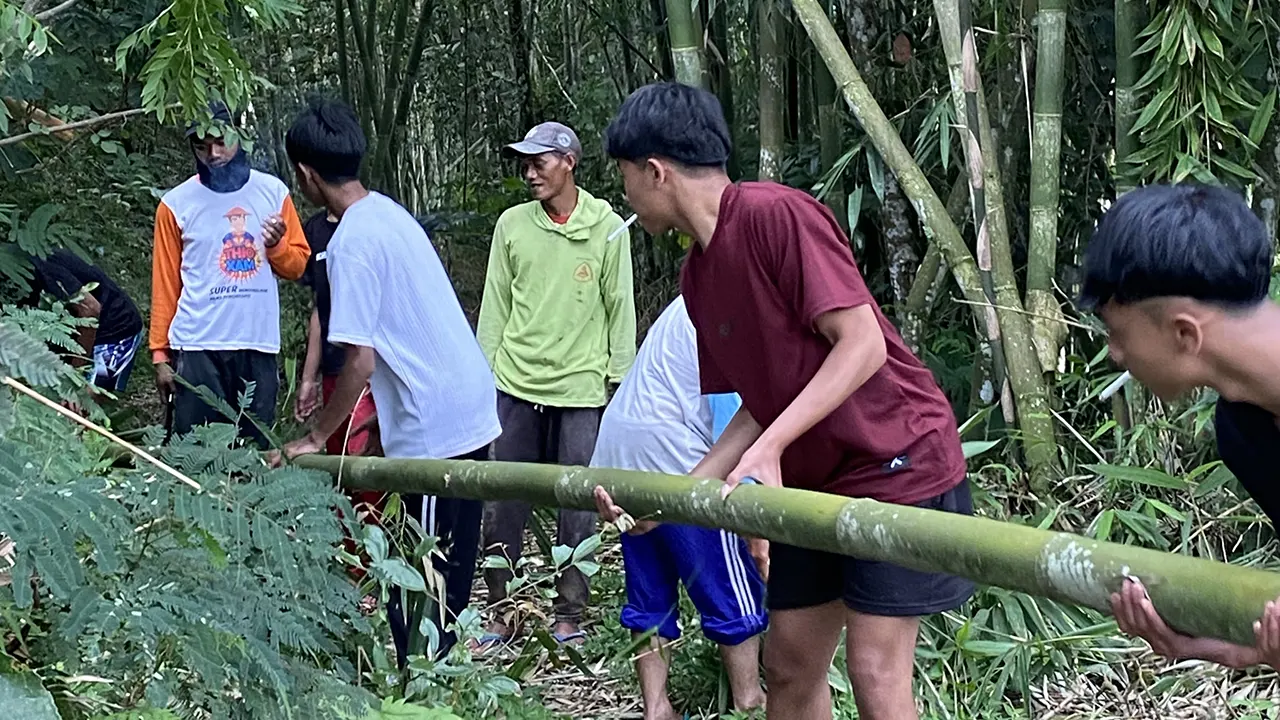 Mahasiswa KKN-PPM UMBY Kelompok 15 bersama warga Dusun Ngepoh Kidul bergotong royong memotong bambu untuk untuk pemasangan jaring penutup talang air, Minggu (8/2/2026). Foto: pribadi
