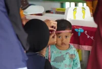 Seorang balita menjalani pengukuran lingkar kepala oleh petugas saat kegiatan posyandu di Desa Geneng, Ngawi. Pemeriksaan ini menjadi bagian dari upaya deteksi dini stunting dan pemantauan tumbuh kembang anak. Foto: Dokumentasi pribadi Kelompok 97 KKN UNS