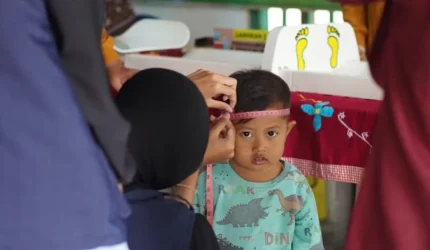 Seorang balita menjalani pengukuran lingkar kepala oleh petugas saat kegiatan posyandu di Desa Geneng, Ngawi. Pemeriksaan ini menjadi bagian dari upaya deteksi dini stunting dan pemantauan tumbuh kembang anak. Foto: Dokumentasi pribadi Kelompok 97 KKN UNS