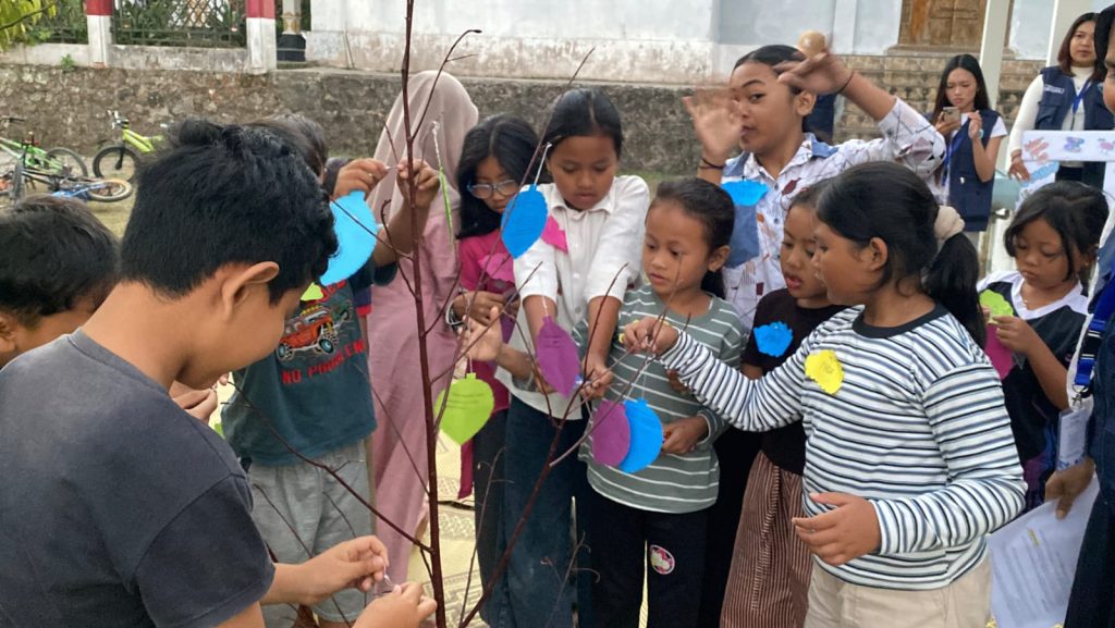 Antusiasme nak-anak Dusun Bono sedang menghias Pohon Harapan dengan menggantung daun berisi harapan dan cita-cita mereka. Sumber: Dok. Pribadi/KKN-PPM UMBY Kelompok 18